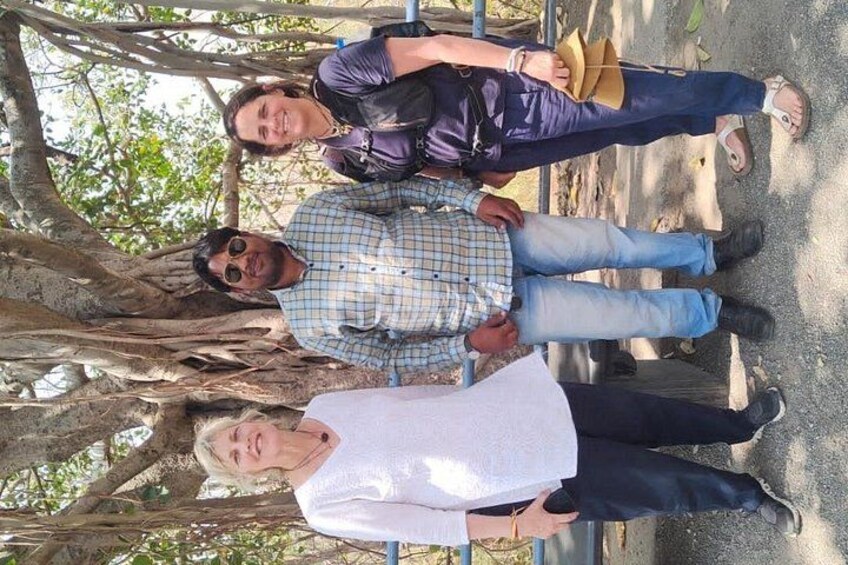 Three people standing under a tree with a metal railing. 3