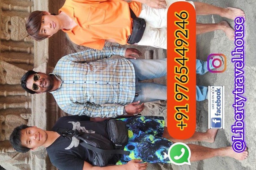 A group of people standing in front of a stone structure with a contact number and social media handles displayed. 4