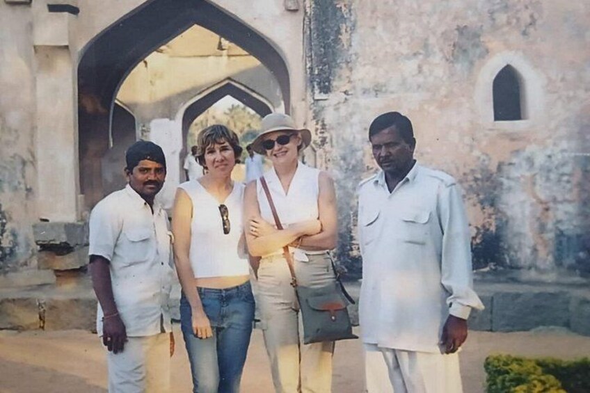 A group of people standing in front of a historic building with arches. 1