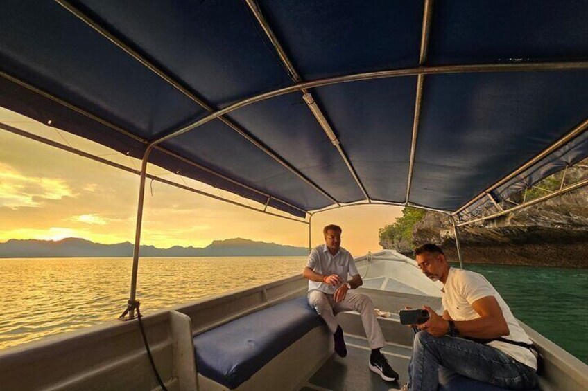 Twee personen in een boot, met een zonsondergang op de achtergrond. 5