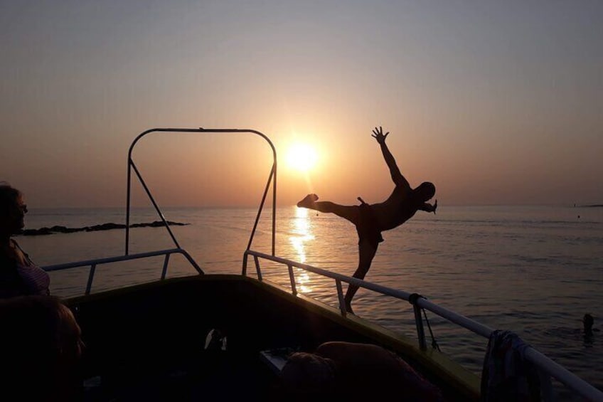 A person performing a handstand on a boat with the sun setting in the background. 5