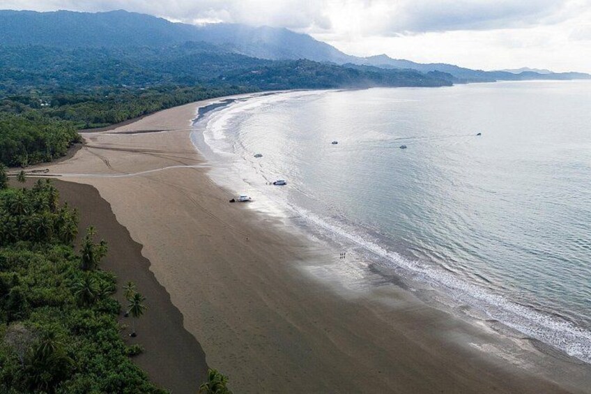 Un paysage côtier avec une plage de sable, une mer calme et des montagnes à l’horizon. 3