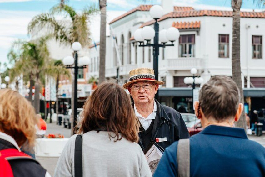 A street scene with palm trees, buildings, and a person wearing a straw hat. 4