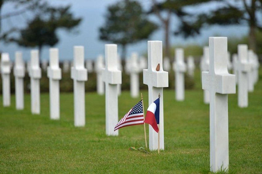 Een begraafplaats met witte kruisen en een Amerikaanse vlag. 2