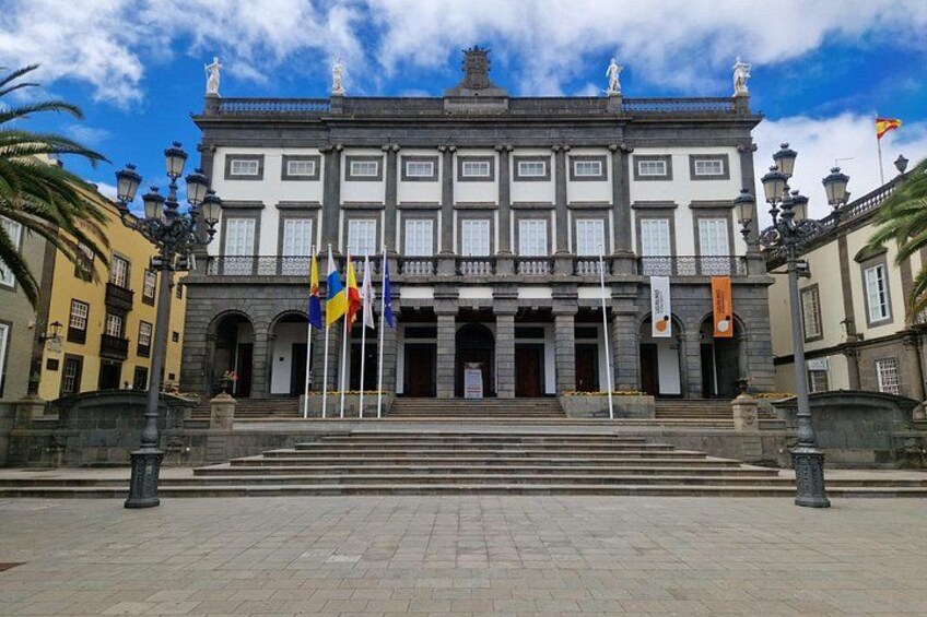 A historic building with a grand entrance, multiple flags, and classical architecture. 2
