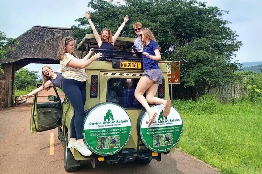 Four people on a safari vehicle with a sign that reads "Devine African Safaris". 1