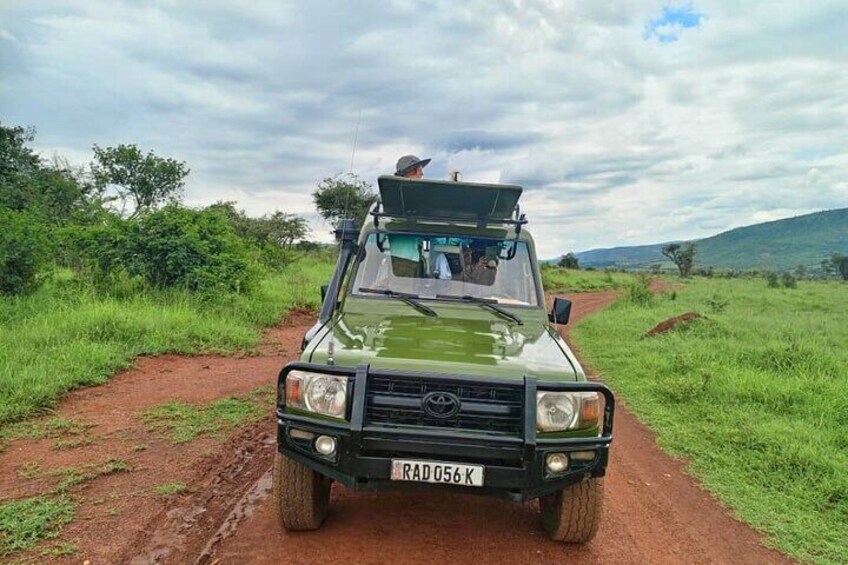 A green off-road vehicle on a dirt path surrounded by greenery. 2
