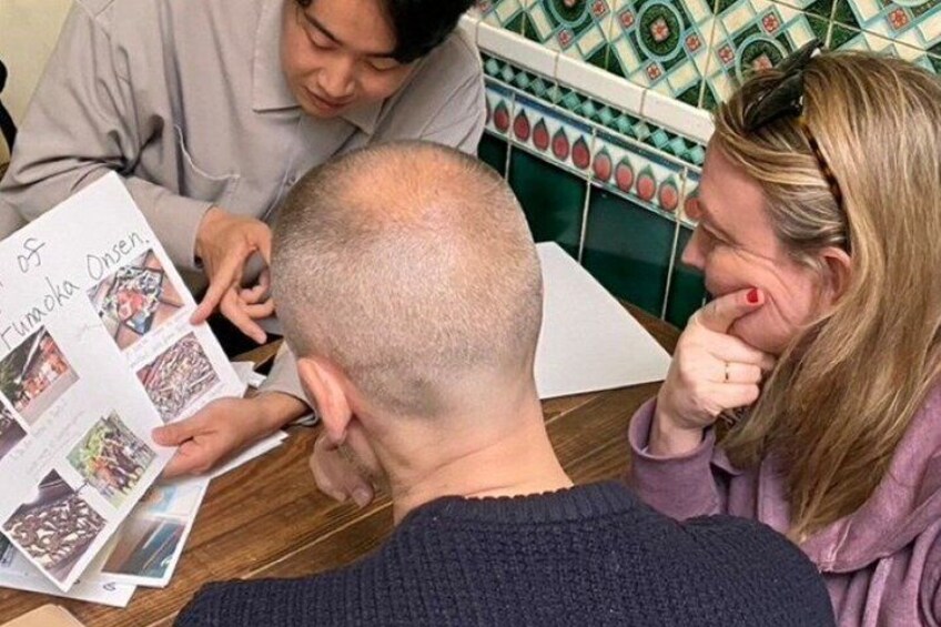 A person with a shaved head, a book with pictures, and a tiled wall in the background. 3