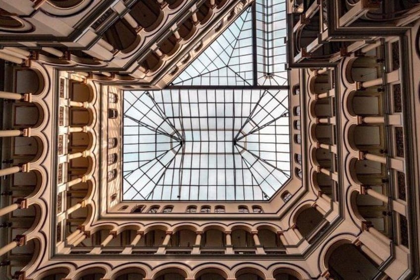 A grand architectural interior with a large glass ceiling, ornate columns, and a symmetrical design. 3