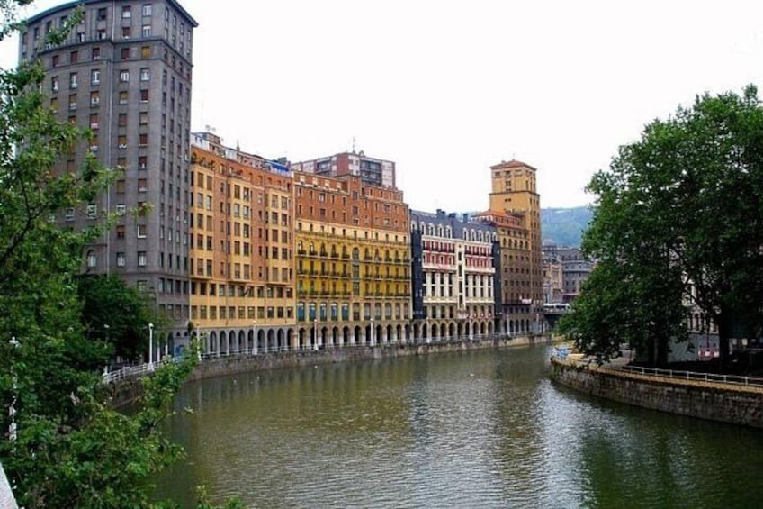 A river with buildings along its banks, a bridge, and trees. 5