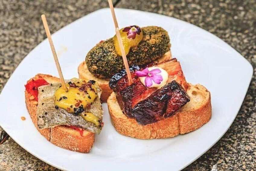 Three pieces of toast with various toppings and a flower on a white plate. 1