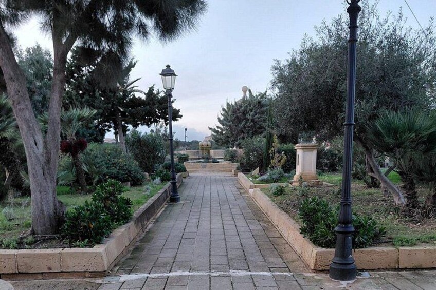 Un sendero pavimentado bordeado de vegetación y un farol. 2