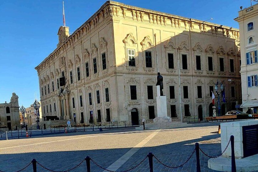 Un edificio histórico con arquitectura clásica, una estatua en la fachada y un cielo azul despejado. 4
