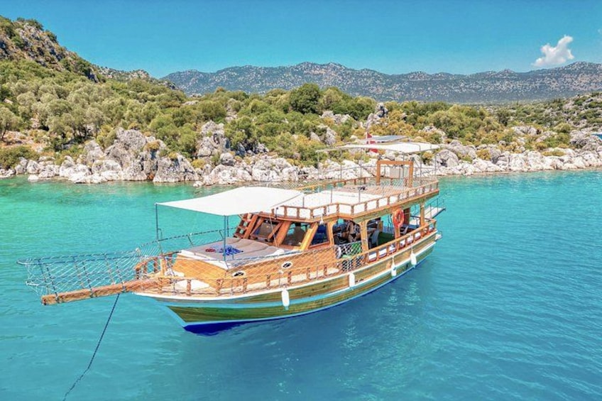 A wooden boat with a canopy, floating on clear turquoise water. 5