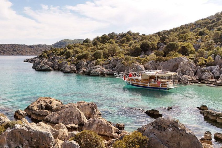 A boat on a turquoise sea, surrounded by rocky terrain and greenery. 2