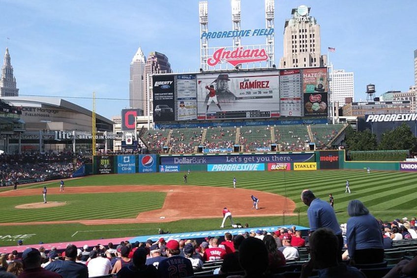 A baseball stadium with a large scoreboard, advertisements, and a crowd of spectators. 3