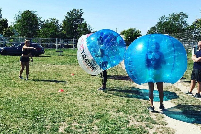 Des personnes manipulent des ballons gonflables transparents sur un terrain herbeux. 2