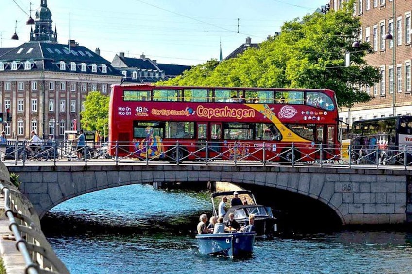 Un autobus à deux étages rouge, portant l’inscription « Copenhague », traverse un pont de pierre au-dessus d’un canal. 1