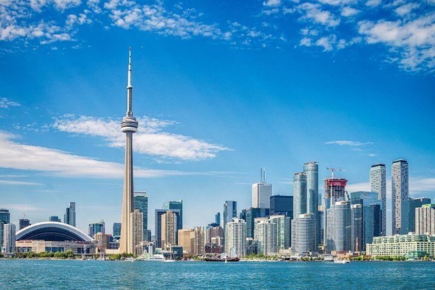 A city skyline with a prominent tower, modern buildings, and a body of water. 2