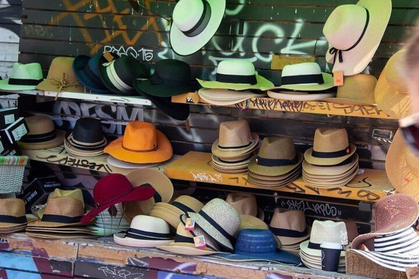 A variety of hats displayed on shelves, with graffiti on the wall behind. 3