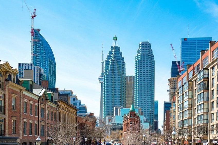 A cityscape with modern skyscrapers, historic buildings, and a clear blue sky. 2