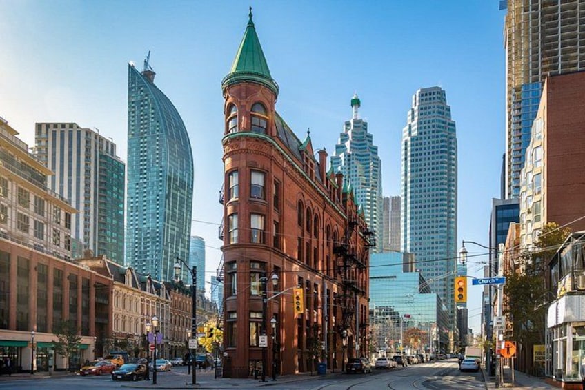 A city street with historic architecture, modern buildings, and a clear sky. 1