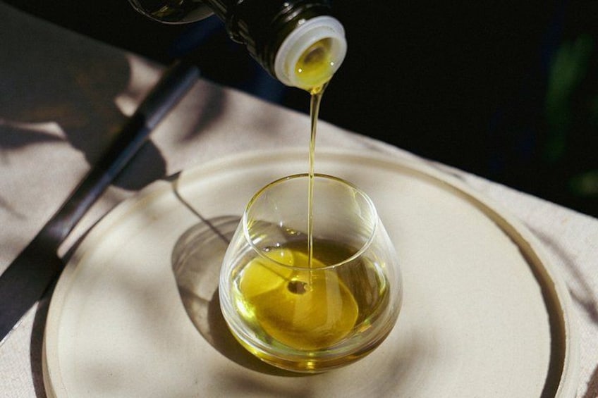 A glass being filled with a yellow liquid, possibly oil, on a plate. 4
