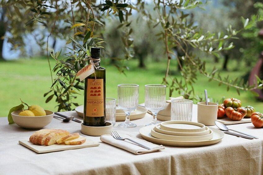 An outdoor dining setup with a bottle of Cretan wine, plates, glasses, and a bowl of fruit. 5