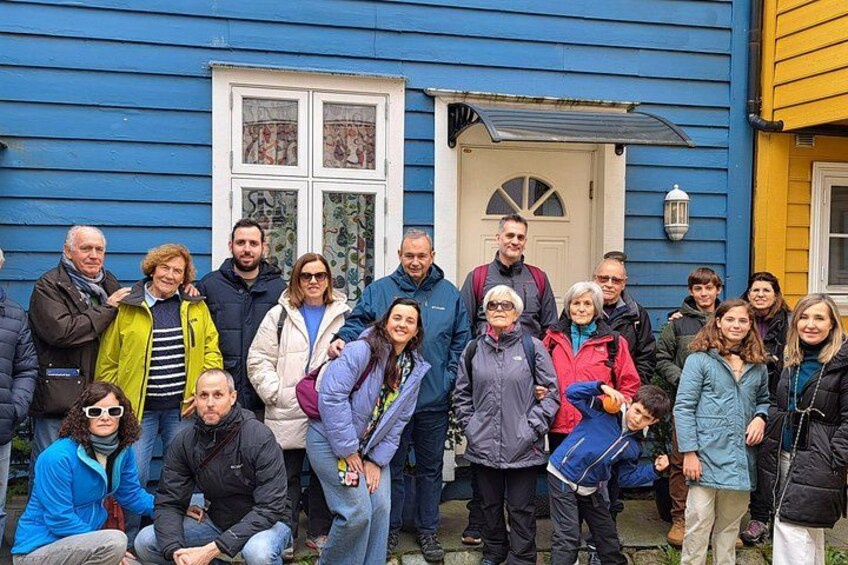 Un grupo de personas de pie frente a una casa azul con puerta y ventanas blancas. 2