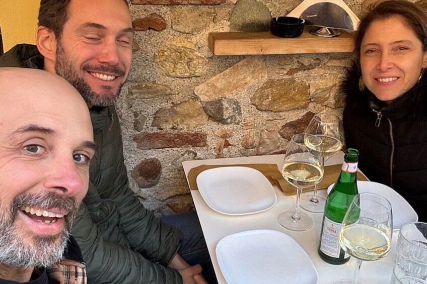 En stenvæg, et bord med tallerkener og glas, og en flaske hvidvin. 2