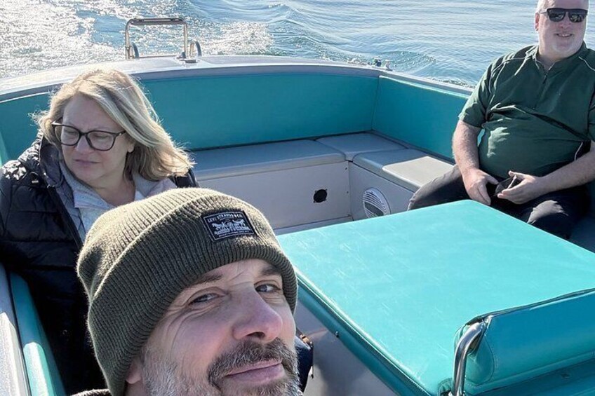 A boat with three people on board, a woman in a black jacket and a man in a green shirt. 3