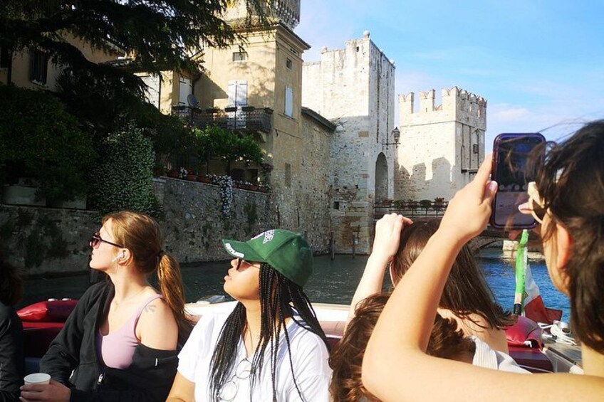 Turistas en un barco cerca de edificios de piedra históricos y un castillo. 1