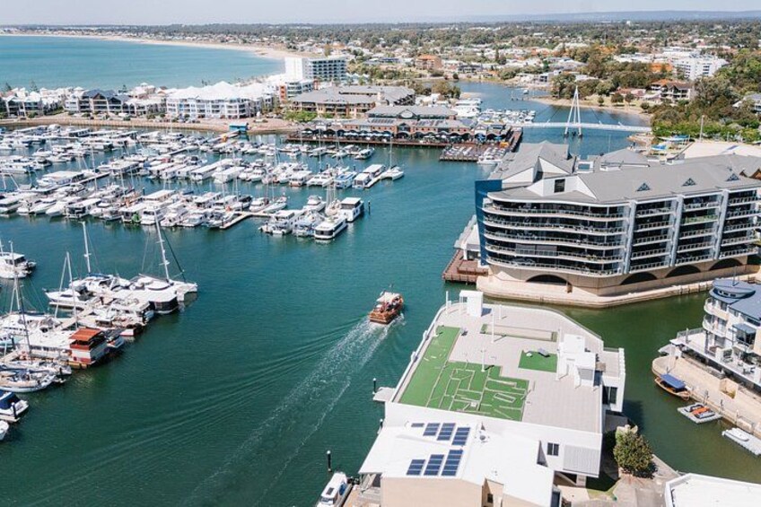 A marina with numerous boats docked, a large building with a unique architecture, and a bridge in the background. 4
