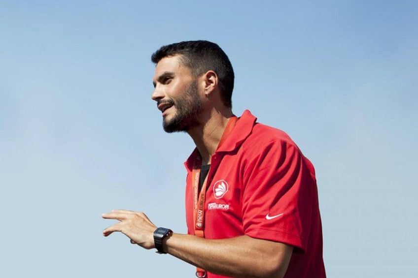 A person wearing a red shirt with a logo, standing outdoors. 1