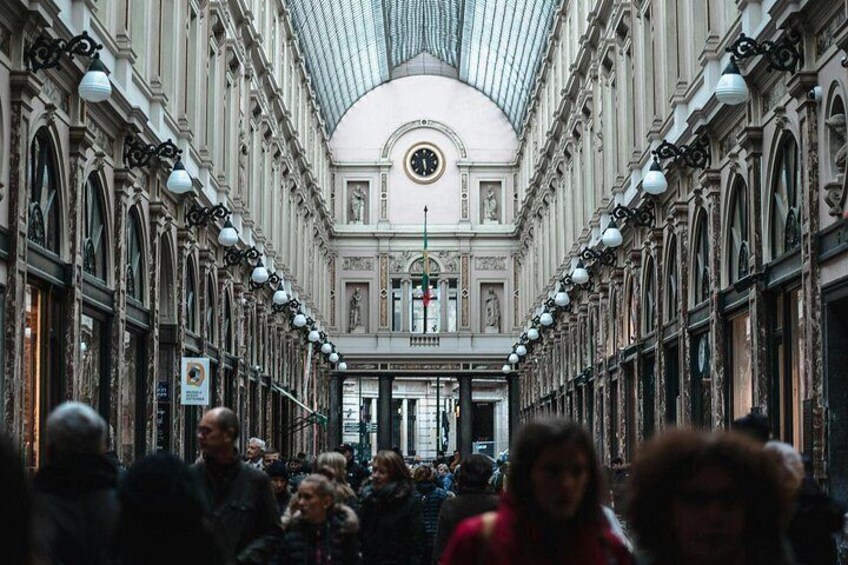 Un espacio interior concurrido y arquitectura ornamentada, con ventanas en arco y un techo alto. 2
