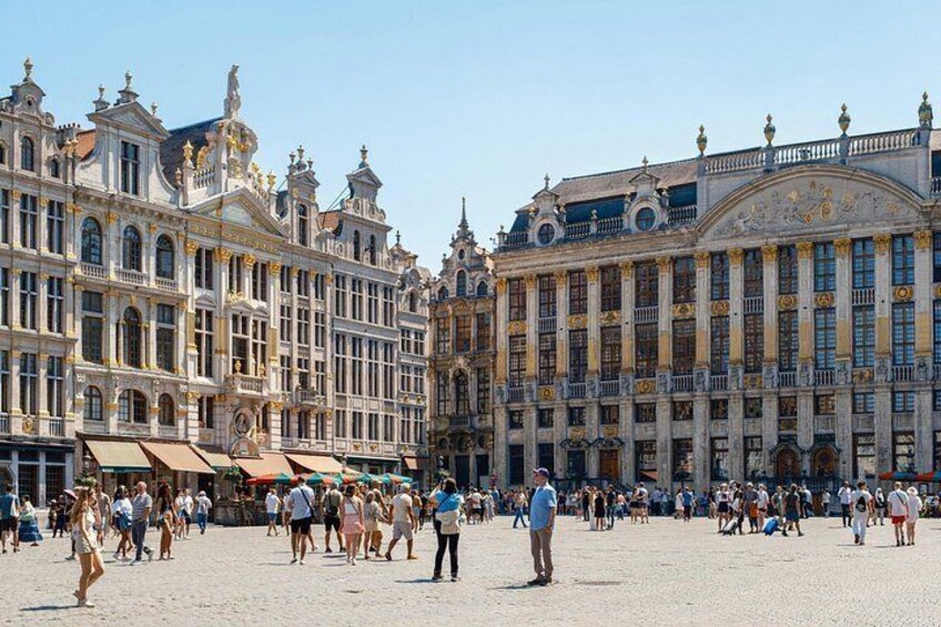 Una plaza histórica europea con edificios ornamentados, una multitud de personas y un cielo despejado. 3