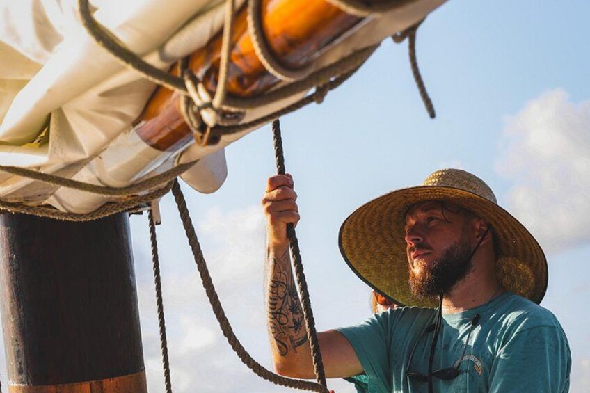 A person wearing a straw hat and a blue shirt, holding onto a rope. 5