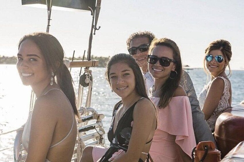 Un groupe de personnes se trouve sur un bateau, avec un ciel dégagé et une eau calme en arrière-plan. 5