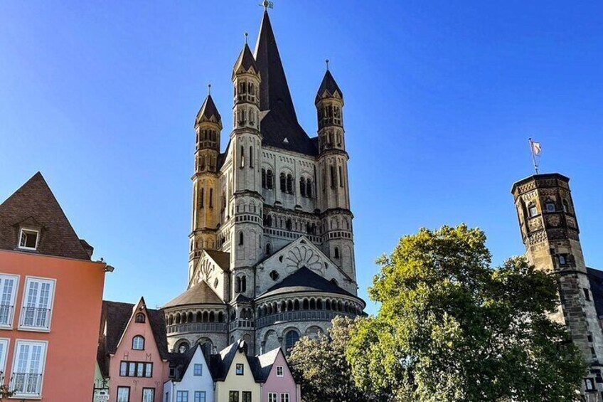 A historic church with a prominent tower and spire, surrounded by colorful buildings. 1