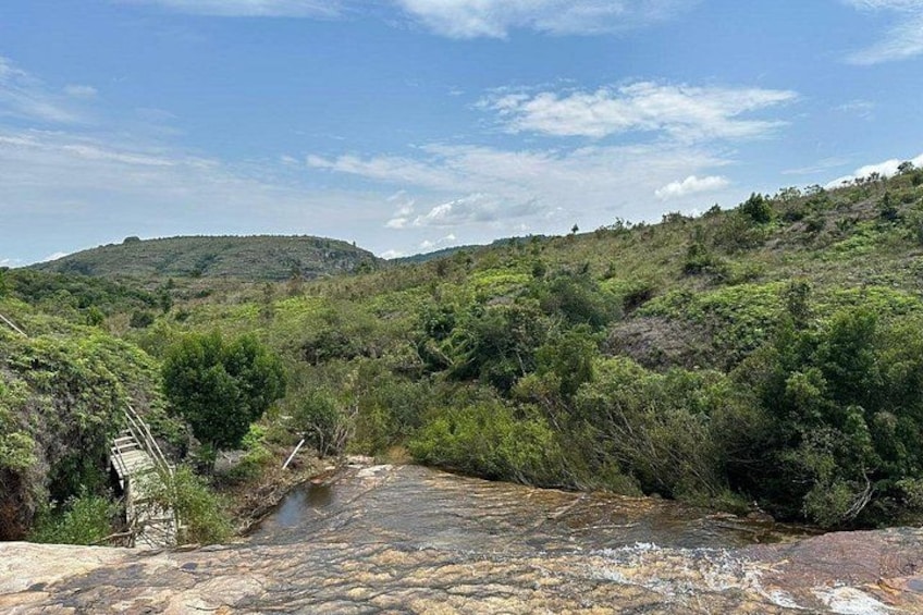 A river flowing through a hilly landscape with dense vegetation and a clear sky. 1