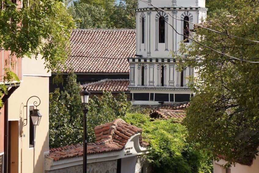 A building with a tiled roof, surrounded by greenery and a street lamp. 2