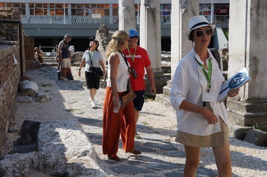 Tourists walking on ancient ruins with columns and stone structures. 5