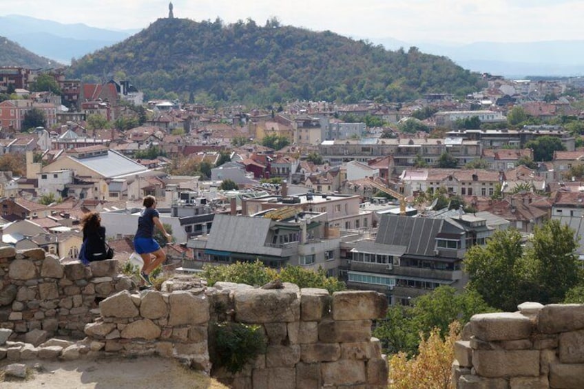 A cityscape with stone walls, a person running, and buildings in the background. 3