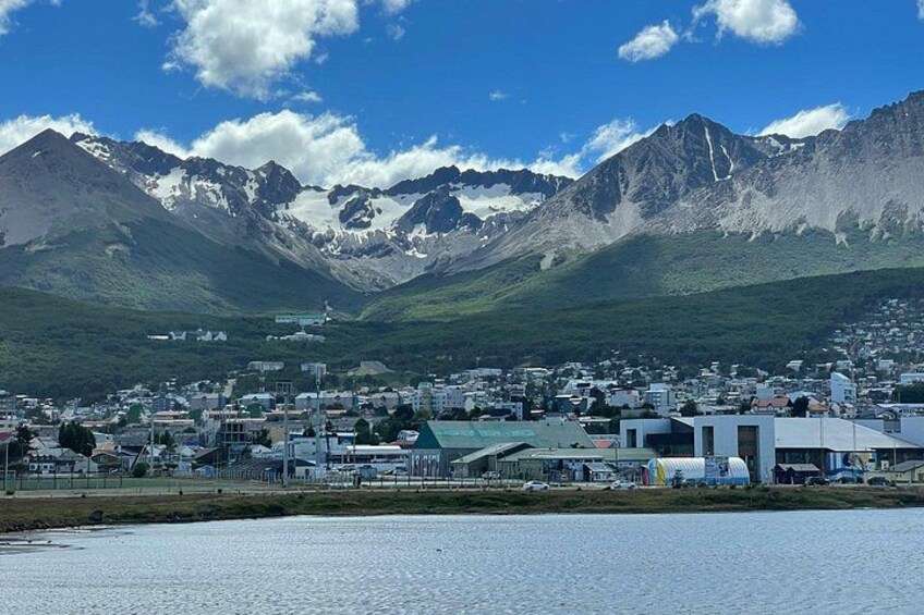 A town by a lake with mountains in the background. 2