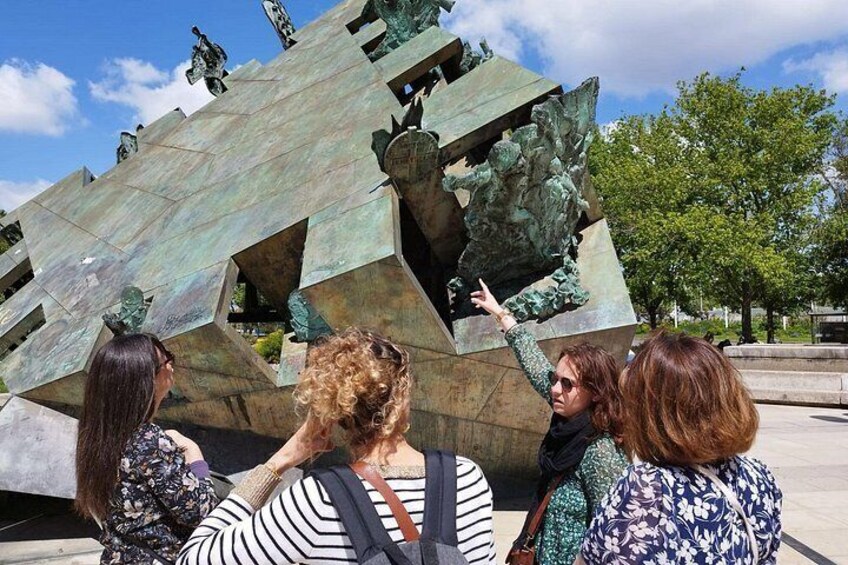 Eine Gruppe von Personen betrachtet eine große, abstrakte Skulptur im Freien. 2