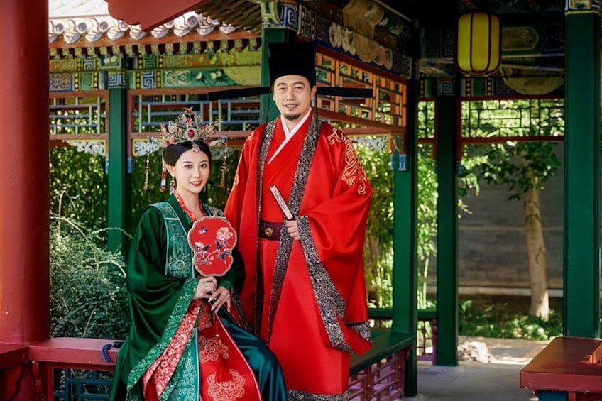 A traditional Chinese pavilion with intricate roof designs and a couple dressed in historical attire. 5