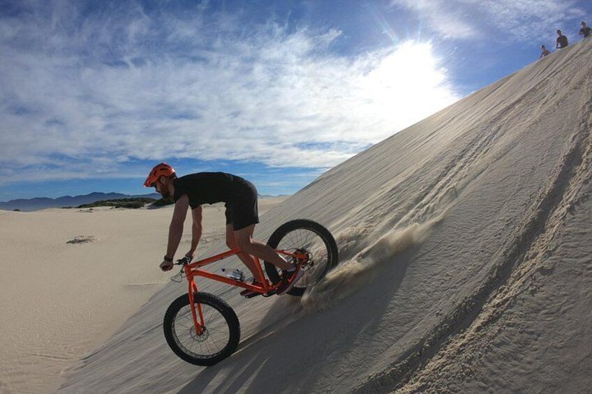En person cykler op ad en sandskrånende bakke. 5