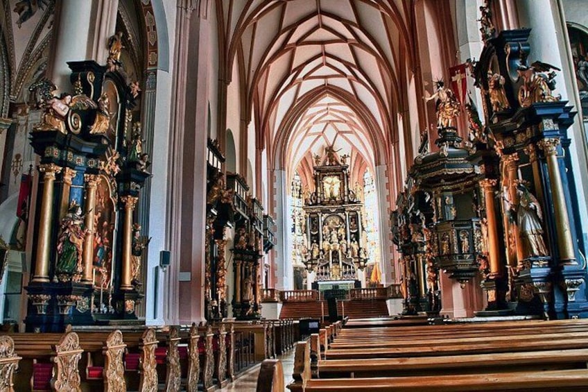 L’intérieur d’une église richement décorée, avec de hauts plafonds en voûte, des rangées de bancs et des autels somptueux. 2