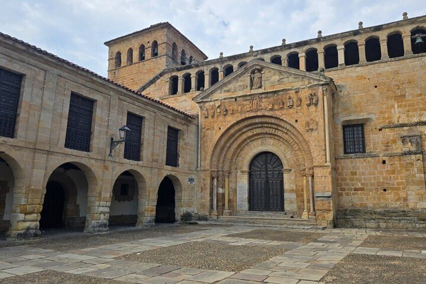 A historic building with a large arched entrance, a bell tower, and a courtyard with stone paving. 4
