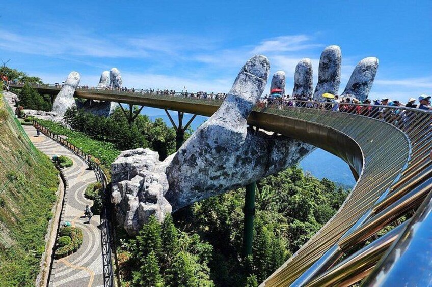 Een grote handsculptuur met een brug erop, een weg en een waterlichaam op de achtergrond. 5
